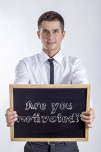 Mann som holder en tavle med skriften: Er du motivert?